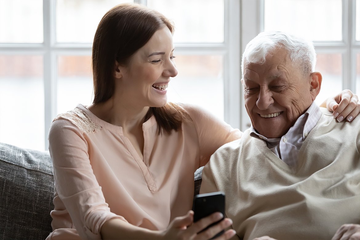 Дедушка с женщиной сидят на диване со смартфоном