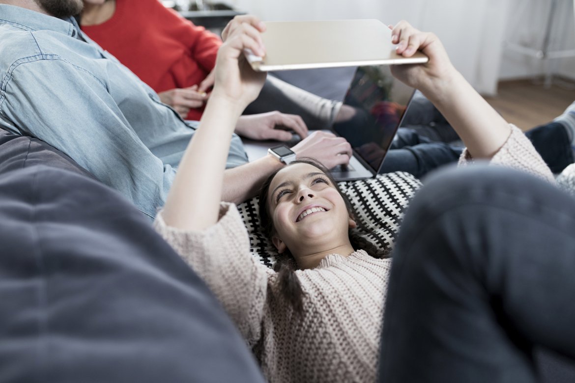Девушка лежит на диване с планшетом в руках